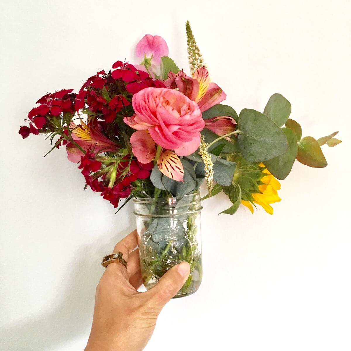 DIY Wedding Flowers: a hand holds a jar with flowers