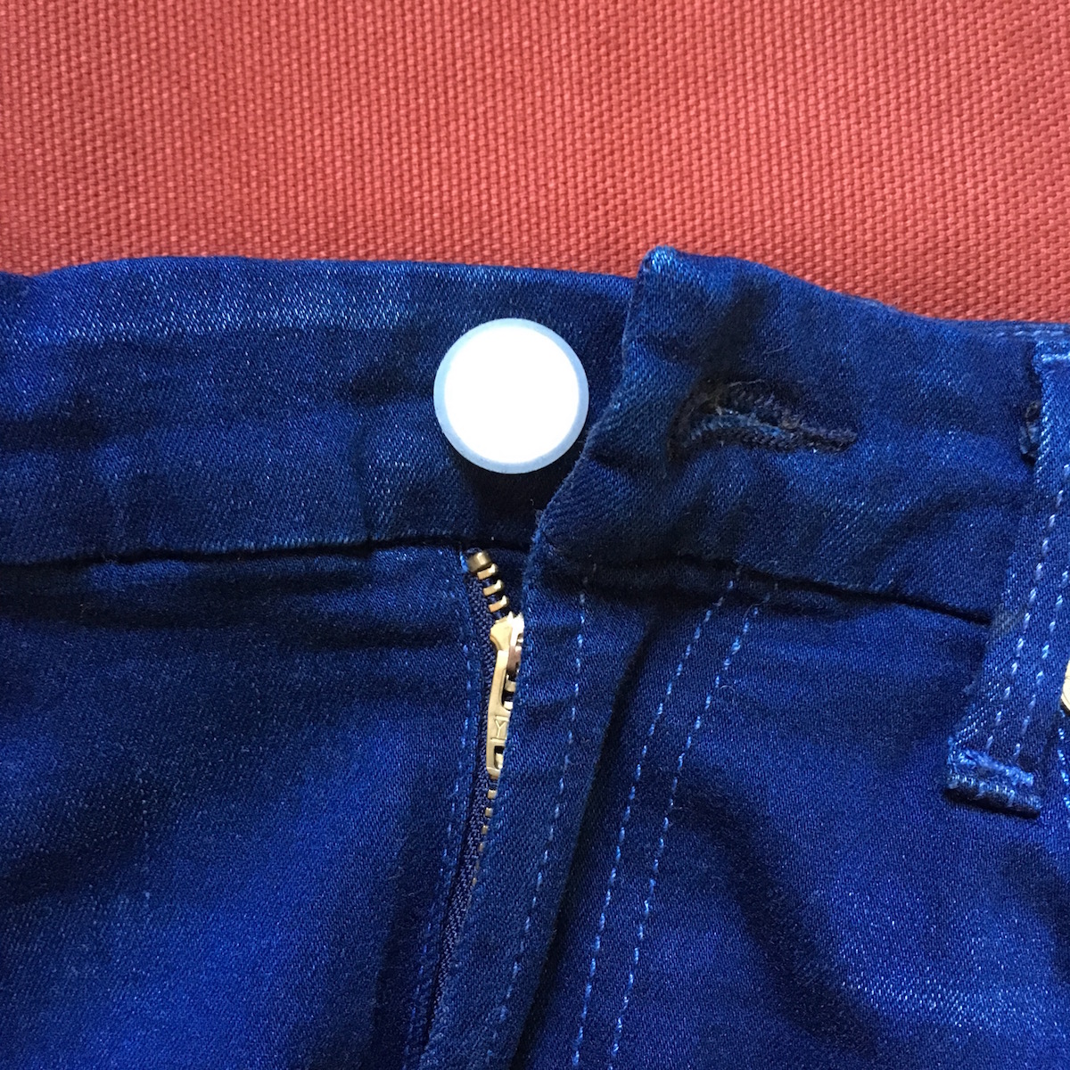 Closeup of blue jeans with Holé button cover.
