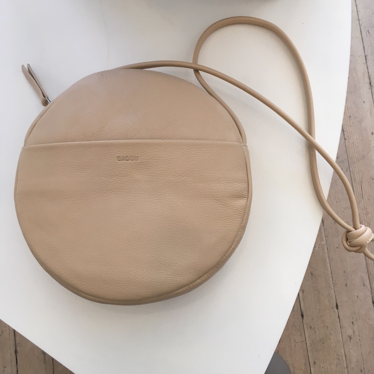 A Baggu Circle Purse in a light brown color on a table at the Baggu store.