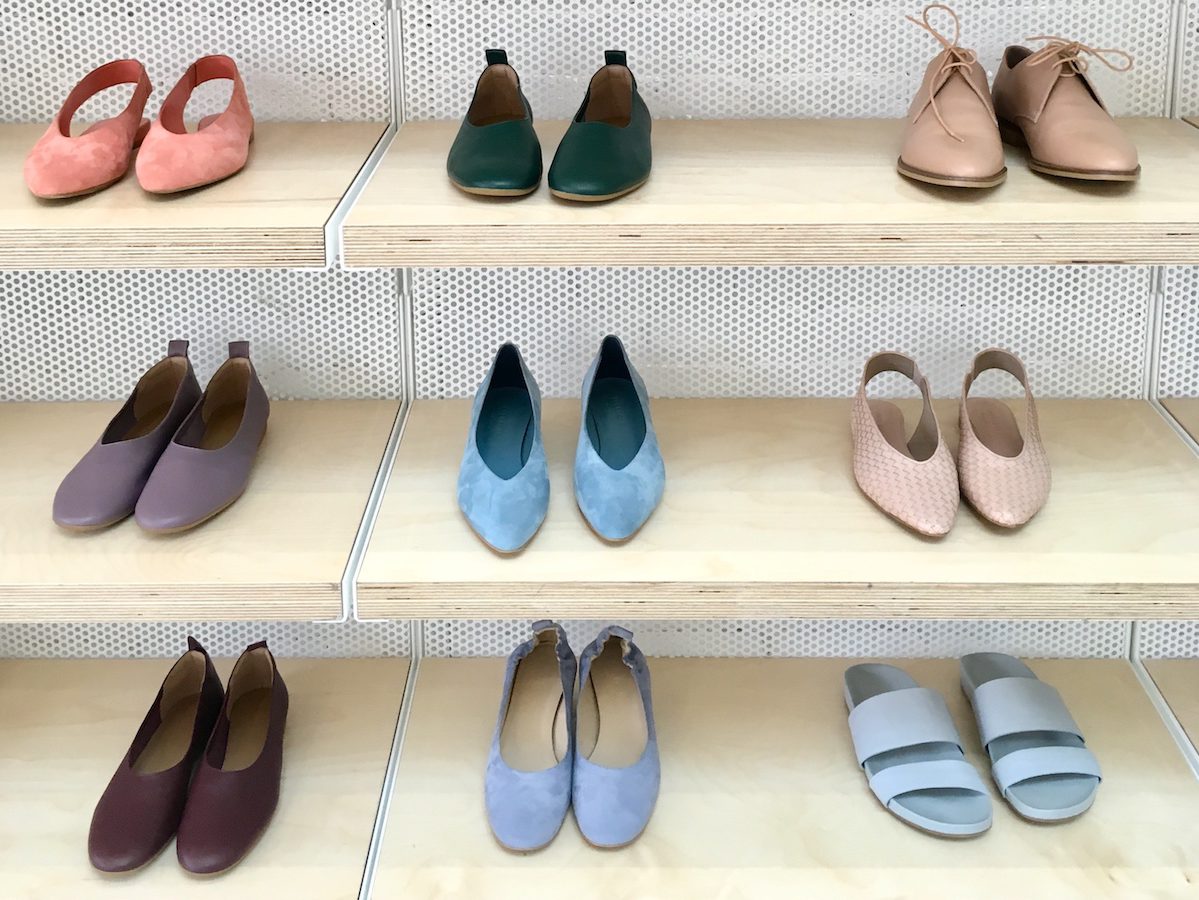 Shelves with shoes on display at Everlane. They are of various colors: orange, pink, green, blue.