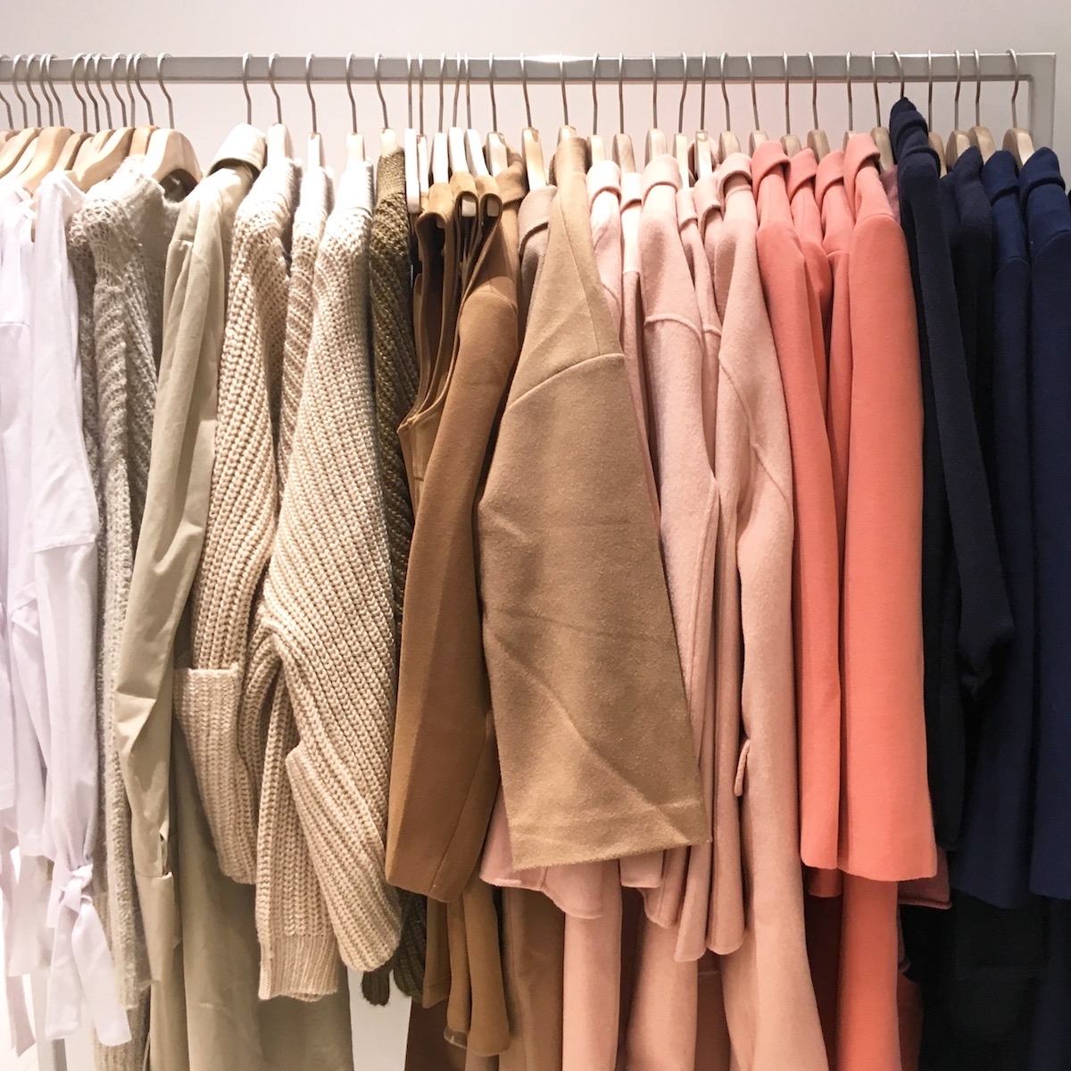 A rack of clothes in neutral colors, pink, and navy