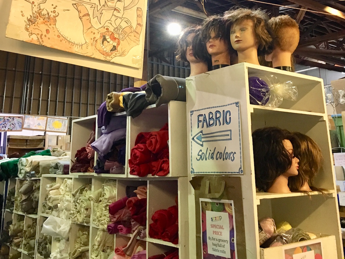 SCRAP SF Tour: Mannequin heads on top of a shelf, and rolls of fabric on cubby shelves.