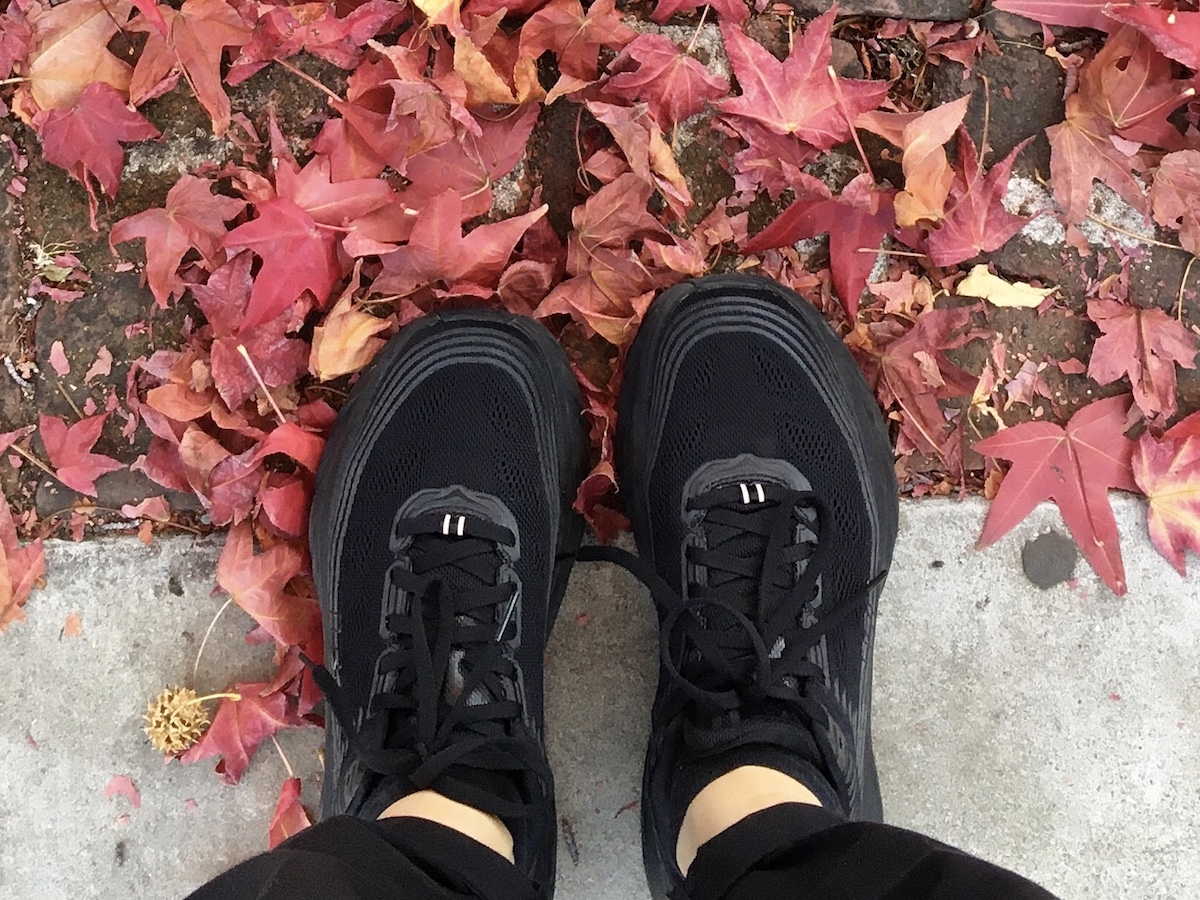 How to style ugly sneakers: Black Hoka One One Bondi sneakers as seen from above on a sidewalk with red leaves.