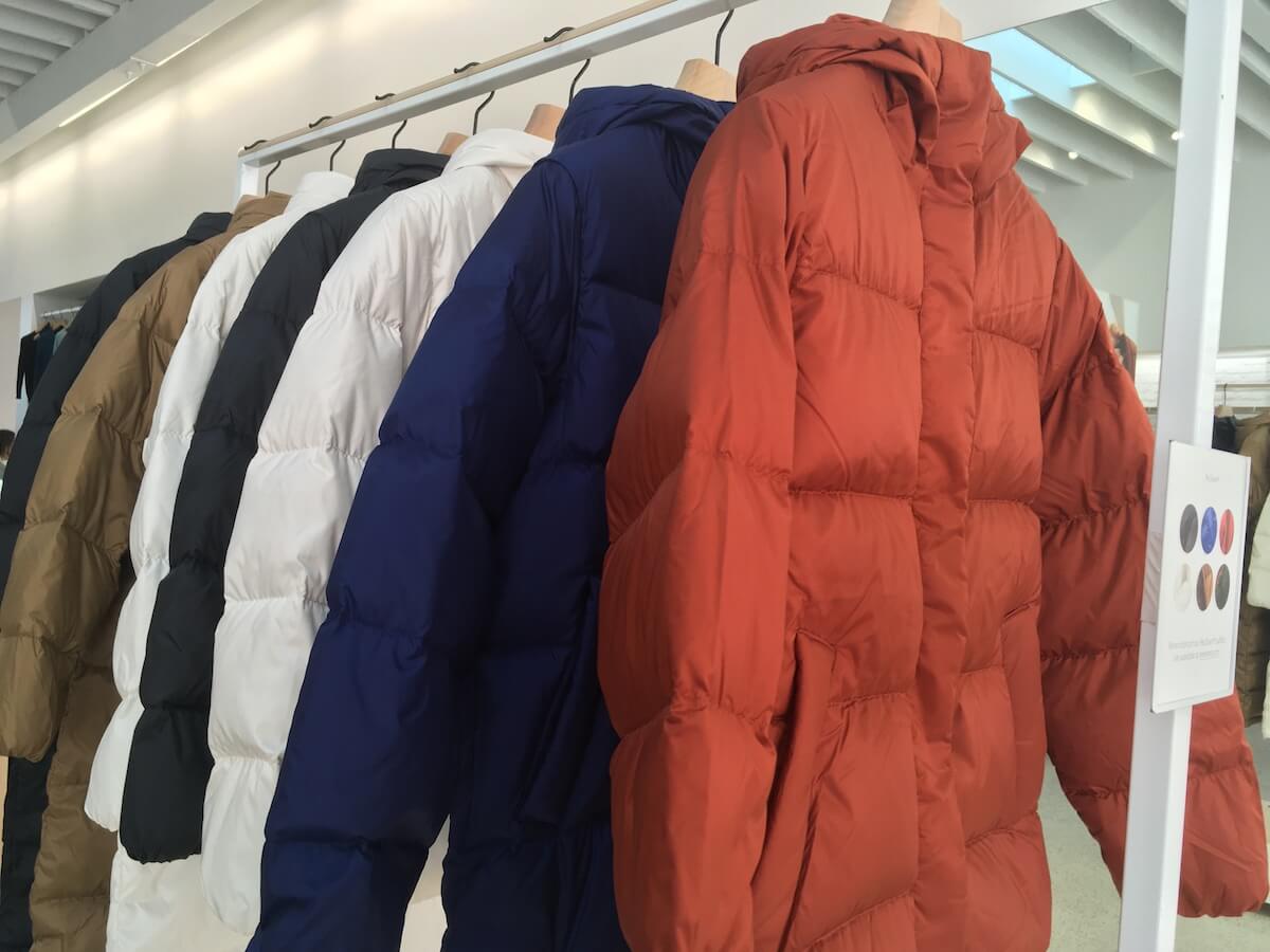 everlane re:down sleeping bag puffer coats and re:down puffy puff jackets hang from a rack in a store.