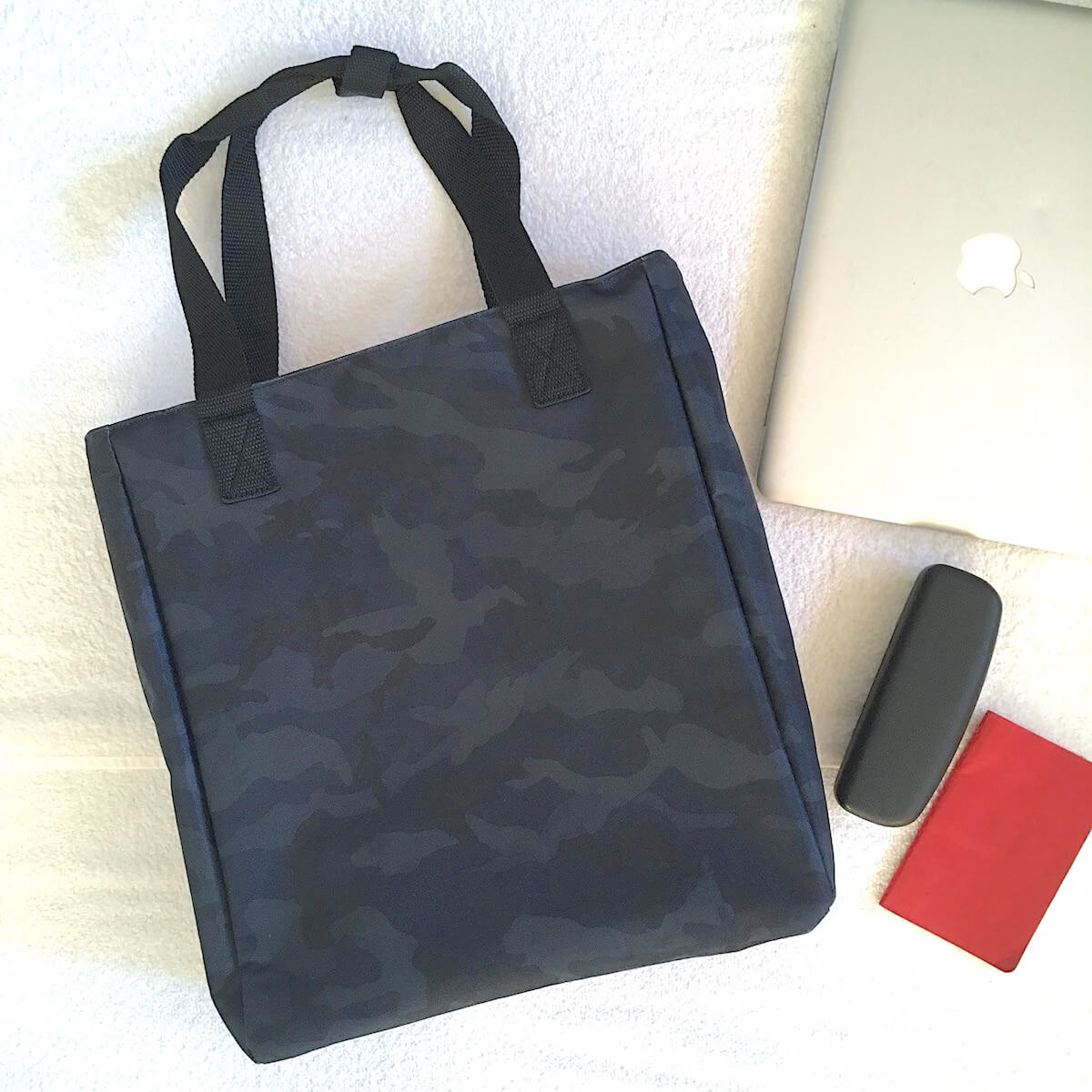 lo & sons edgemont convertible backpack tote review: a flat lay of the bag with a laptop, sunglasses case, and notebook.