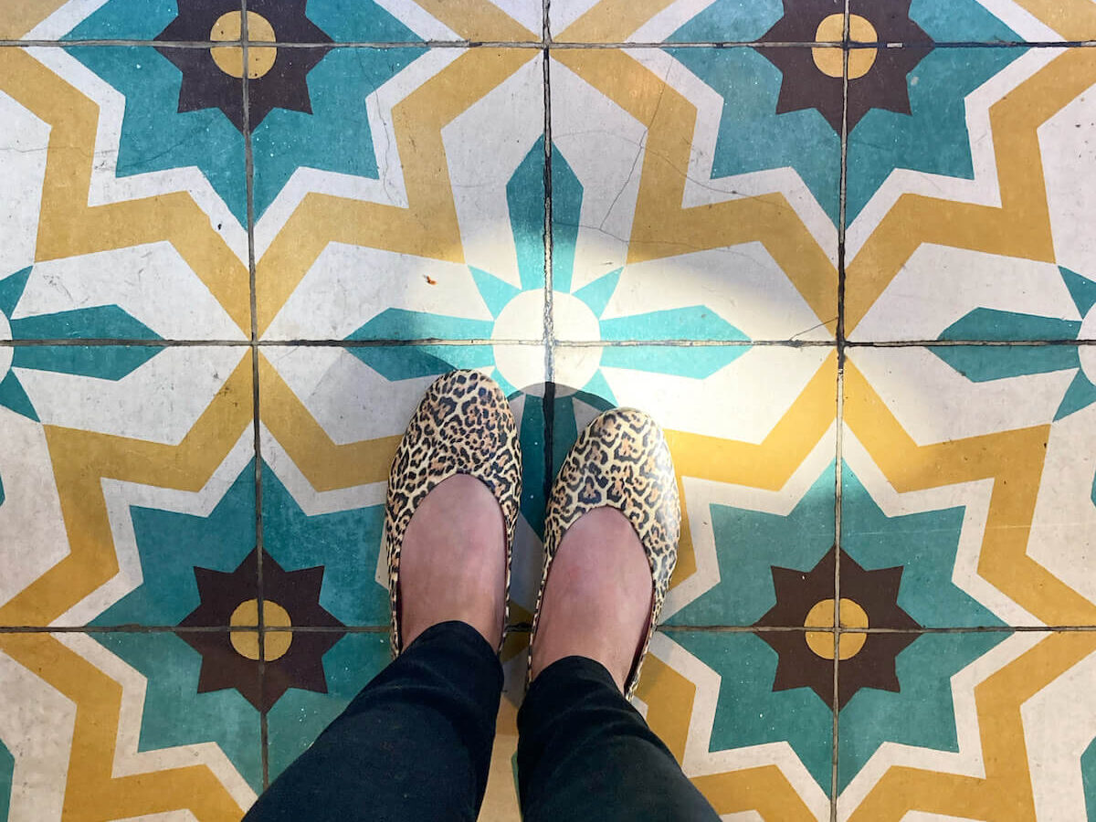 Looking down at dr. liza leopard print flats on colorful tile