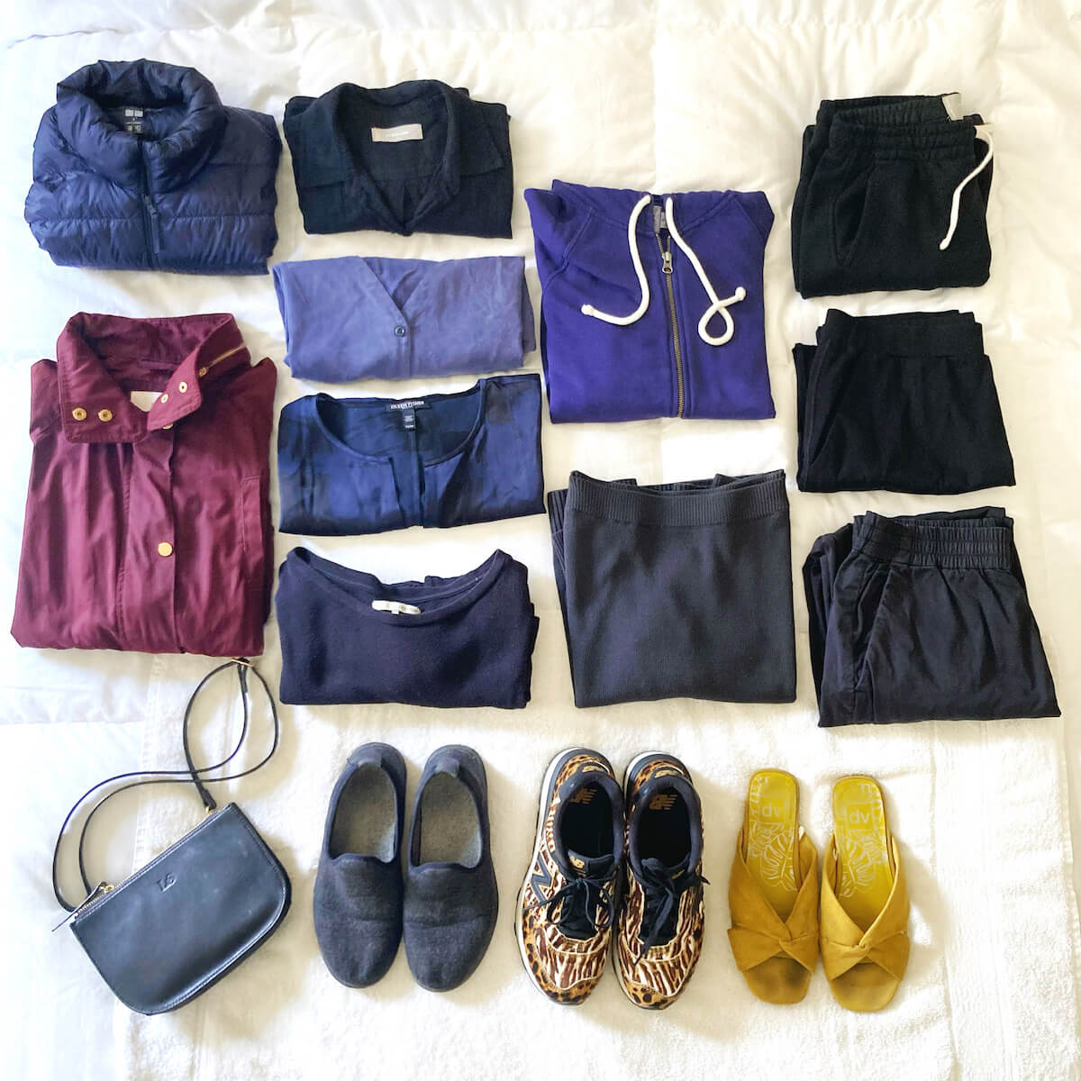 11 pieces of clothing, folded neatly, plus 3 pairs of shoes and a bag, all on a white surface