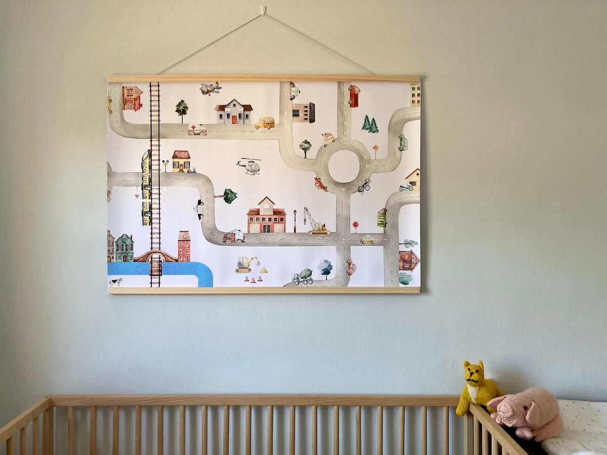 A poster featuring vehicles hung above a crib.