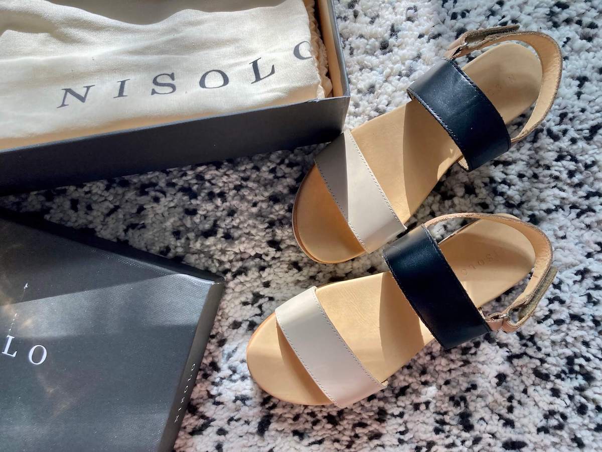 A pair of Nisolo go-to flatform sandals with black and cream straps.