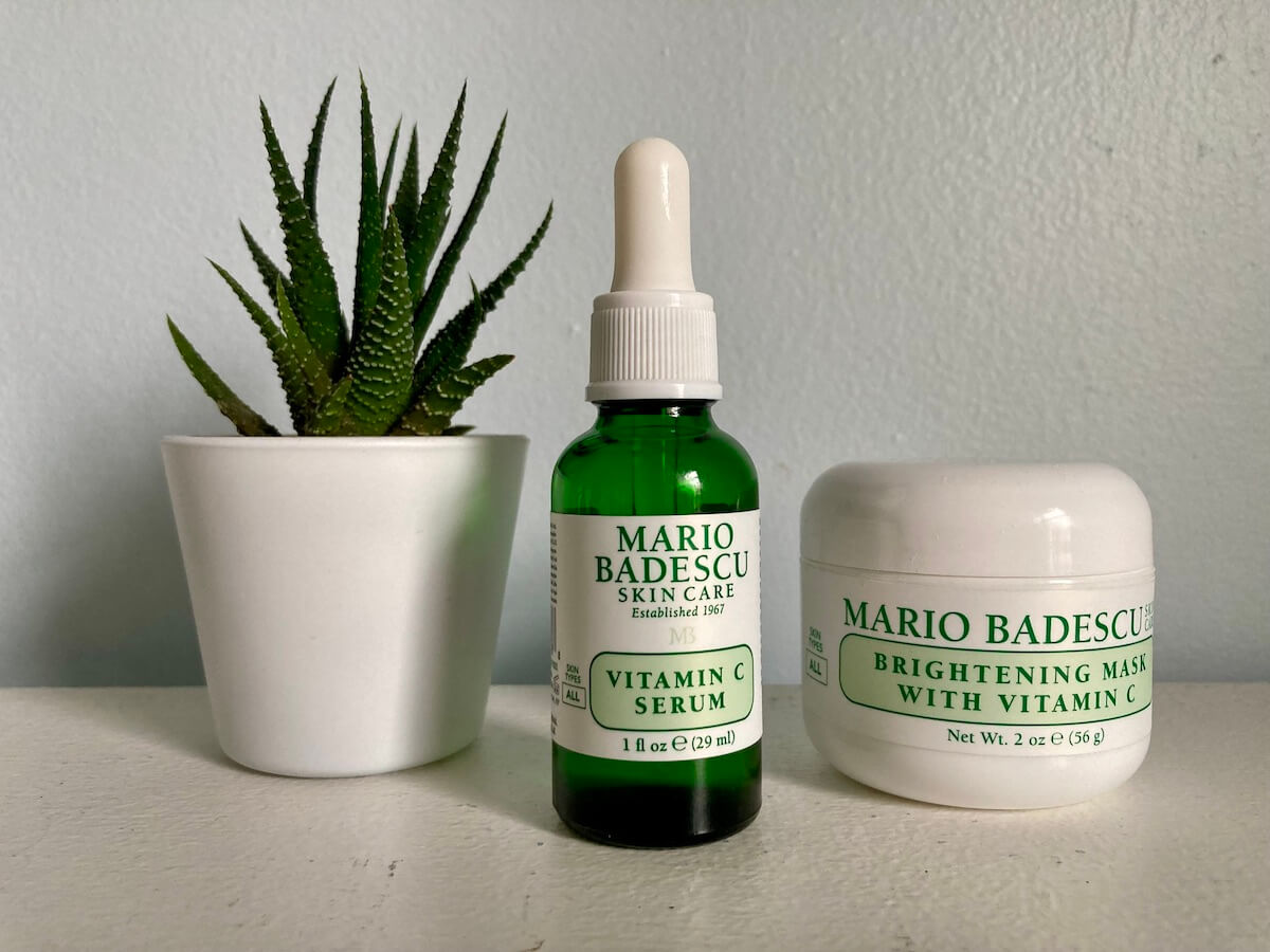 A small plan in a white pot, a bottle of Mario Badescu Vitamin C Serum, and a jar of Mario Badescu Brightening Mask.