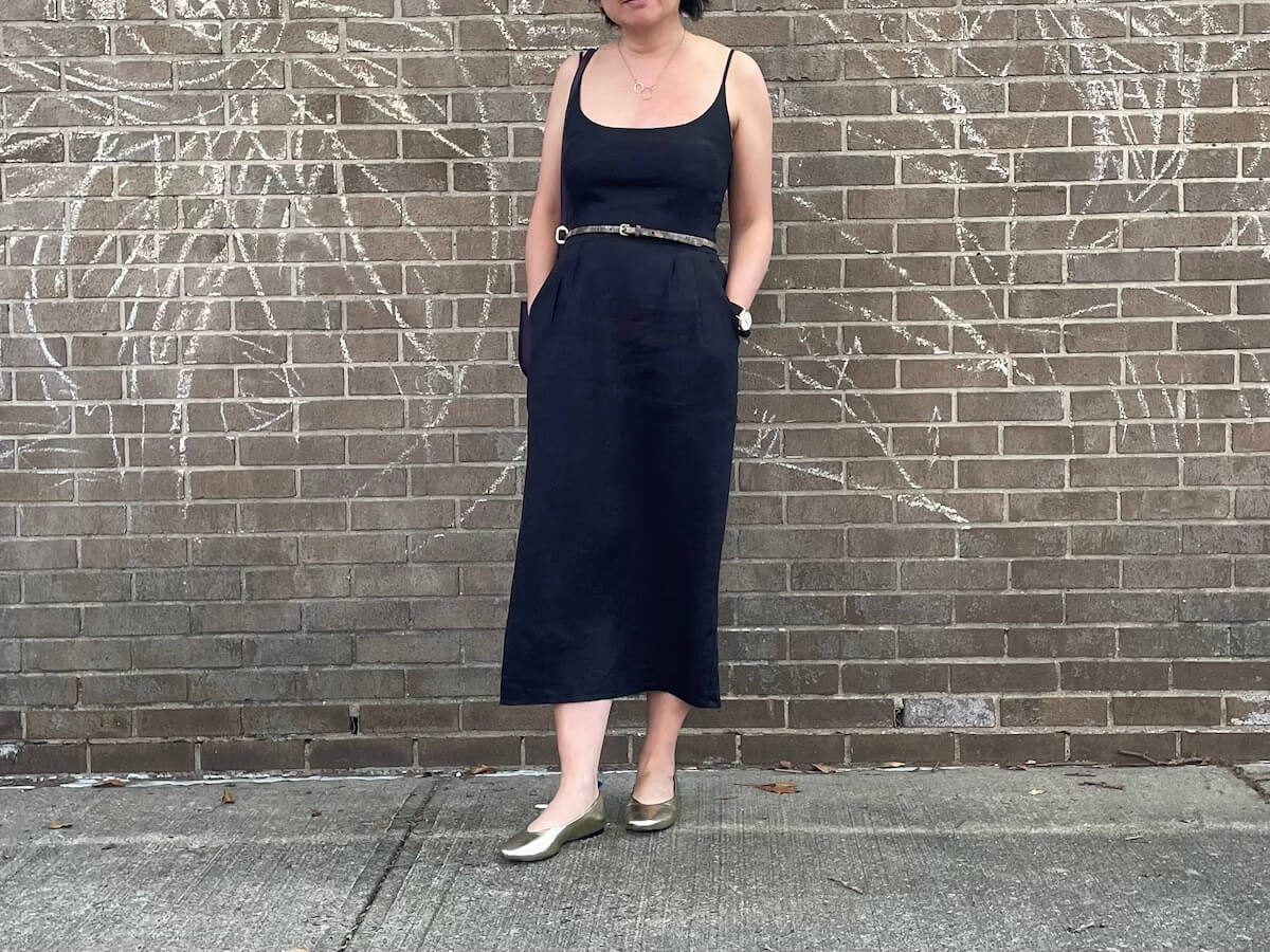 a person wears a linen midi dress in front of a brick wall