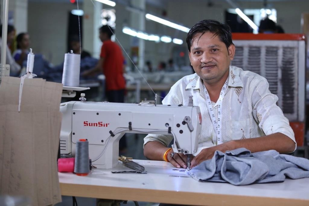 An India man at a workstation with a sewing machine